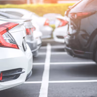 Cars parked closely together in a parking lot with visible white parking lines.
