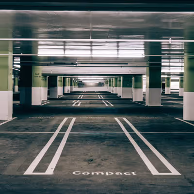 Empty underground parking garage with marked parking spaces and green support columns.